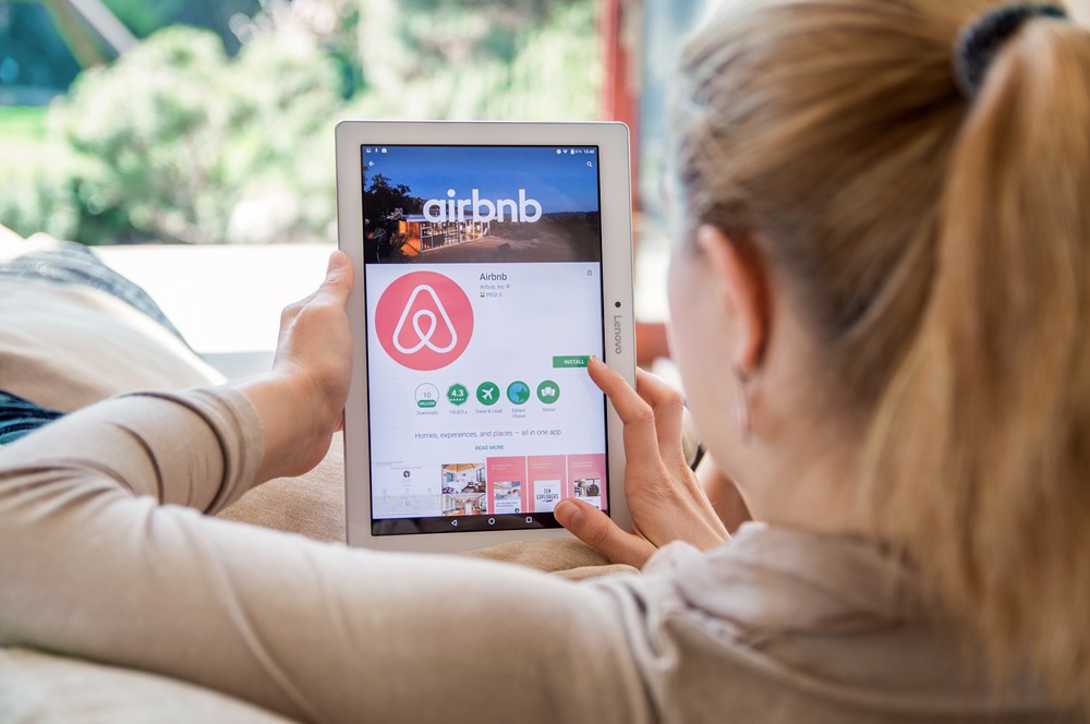 A woman browsing Airbnb's website on a tablet