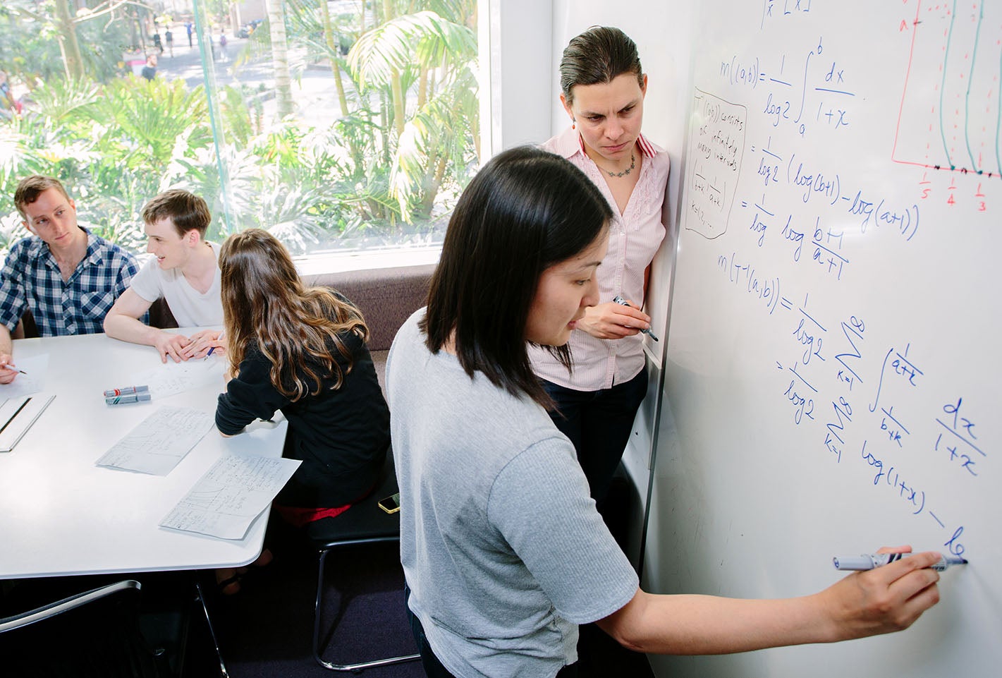 students solving math problems on a whiteboard